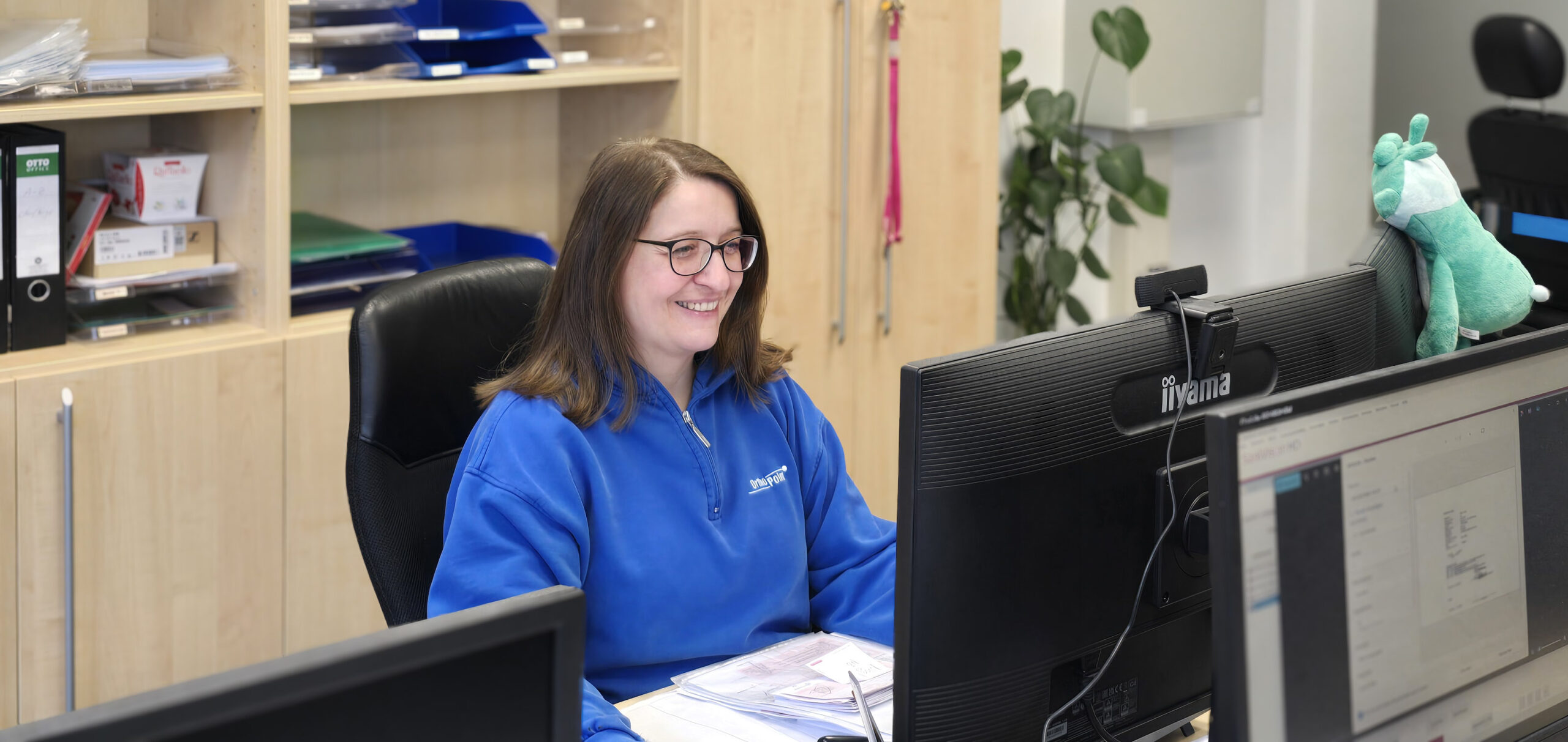 Kauffrau im Sanitätshaus bearbeitet Aufträge am Computer im Büro