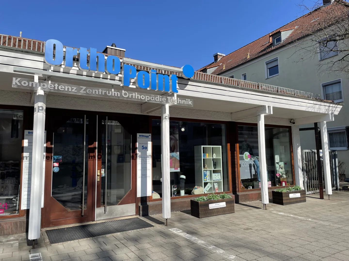 Sanitätshaus OrthoPoint Filiale Erlangen Drausnickstraße von Außen, man sieht Parkplätze und ein Eingang