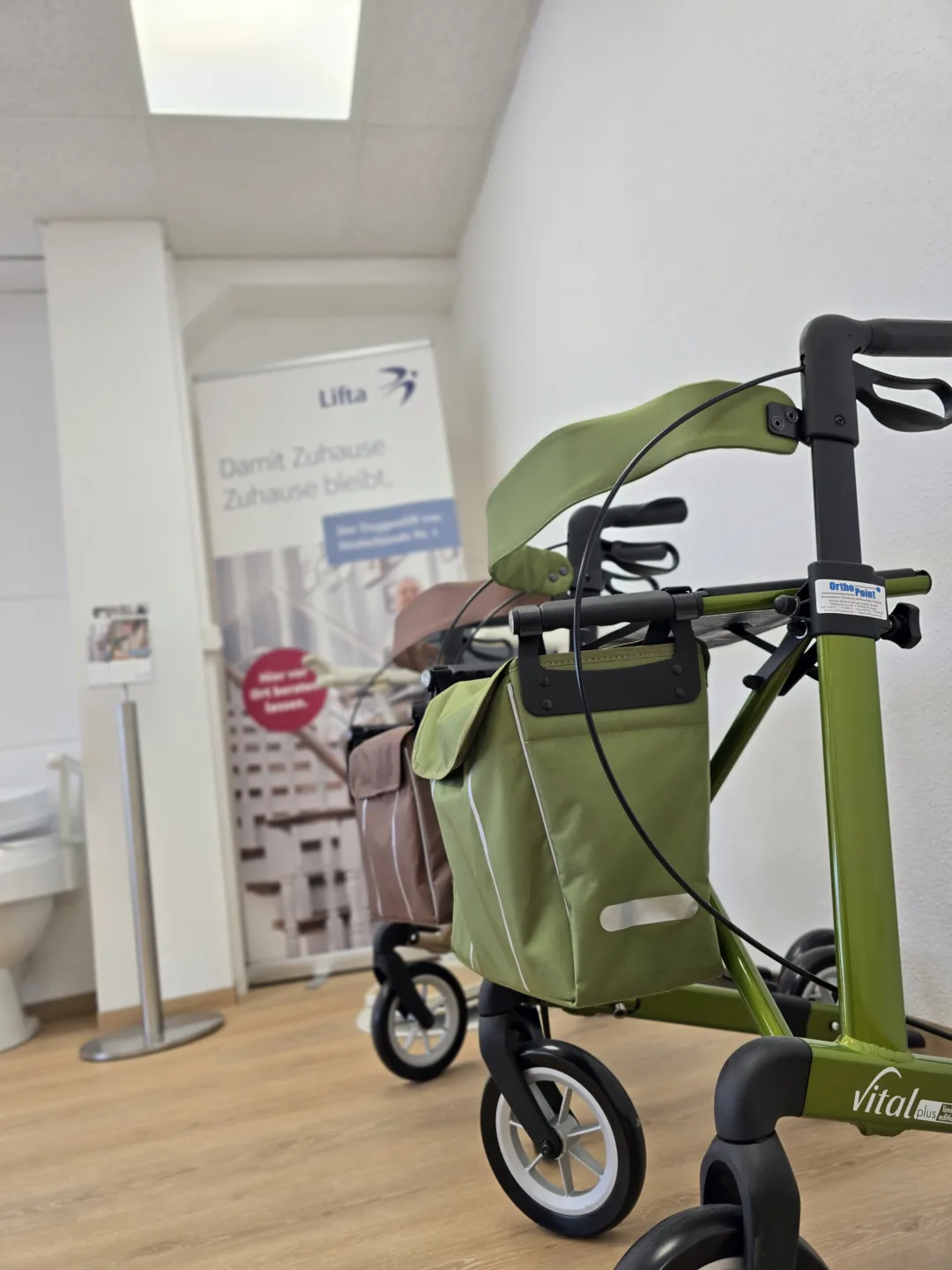 Grüner Rollator vor einem Rollup Plakat in unserer Filiale Erlangen Sonnenstraße