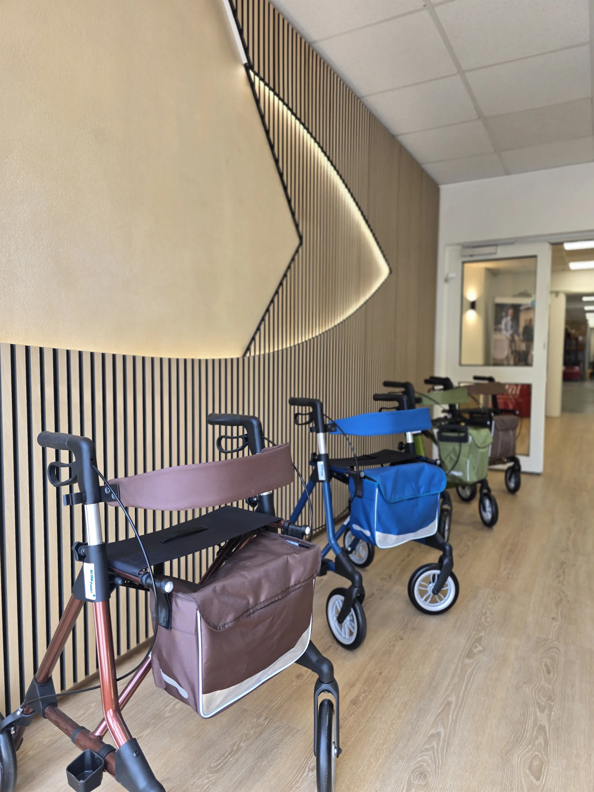 Ausstellung von verschieden farbigen Rollatoren vor einer beleuchteten Holzwand in der Filiale Erlangen Sonnenstraße