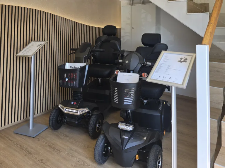 Zwei Elektrorollstühle vor einen beleuchteten Akustikpanelwand in unserer Filiale in Erlangen Sonnenstraße Rehatechnik